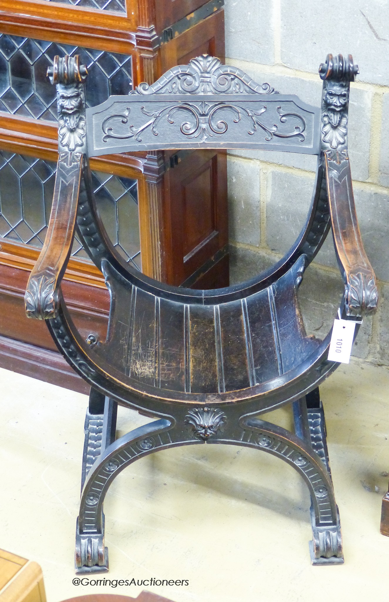 An Ebonised Sagrada style x-frame elbow chair.